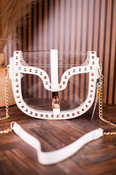 Clear and White Studded Crossbody Bag with gold studs and chain strap on wooden surface with vertical striped background