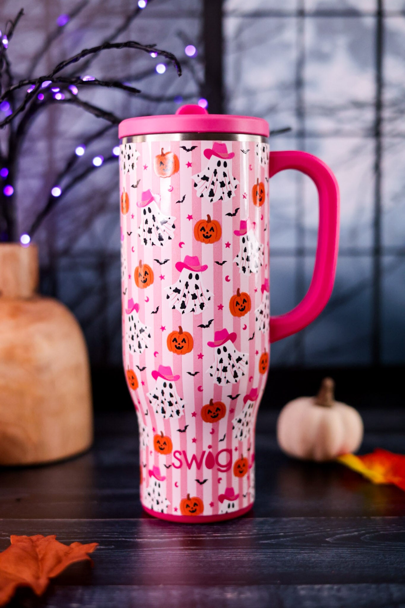 Ghost Town 30oz Mega Mug in pink with Halloween ghost and pumpkin pattern displayed on a dark table with autumn decor