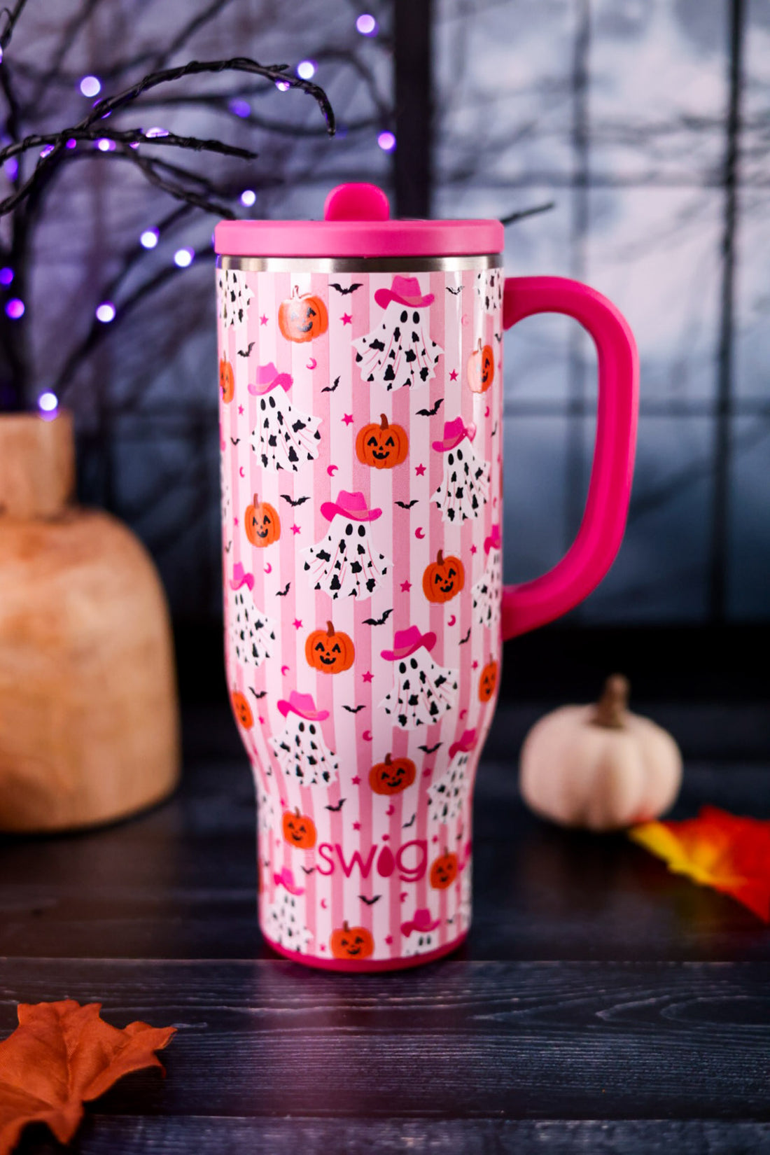 Ghost Town 30oz Mega Mug in pink with Halloween pumpkins and ghost pattern displayed on a dark tabletop with autumn decor