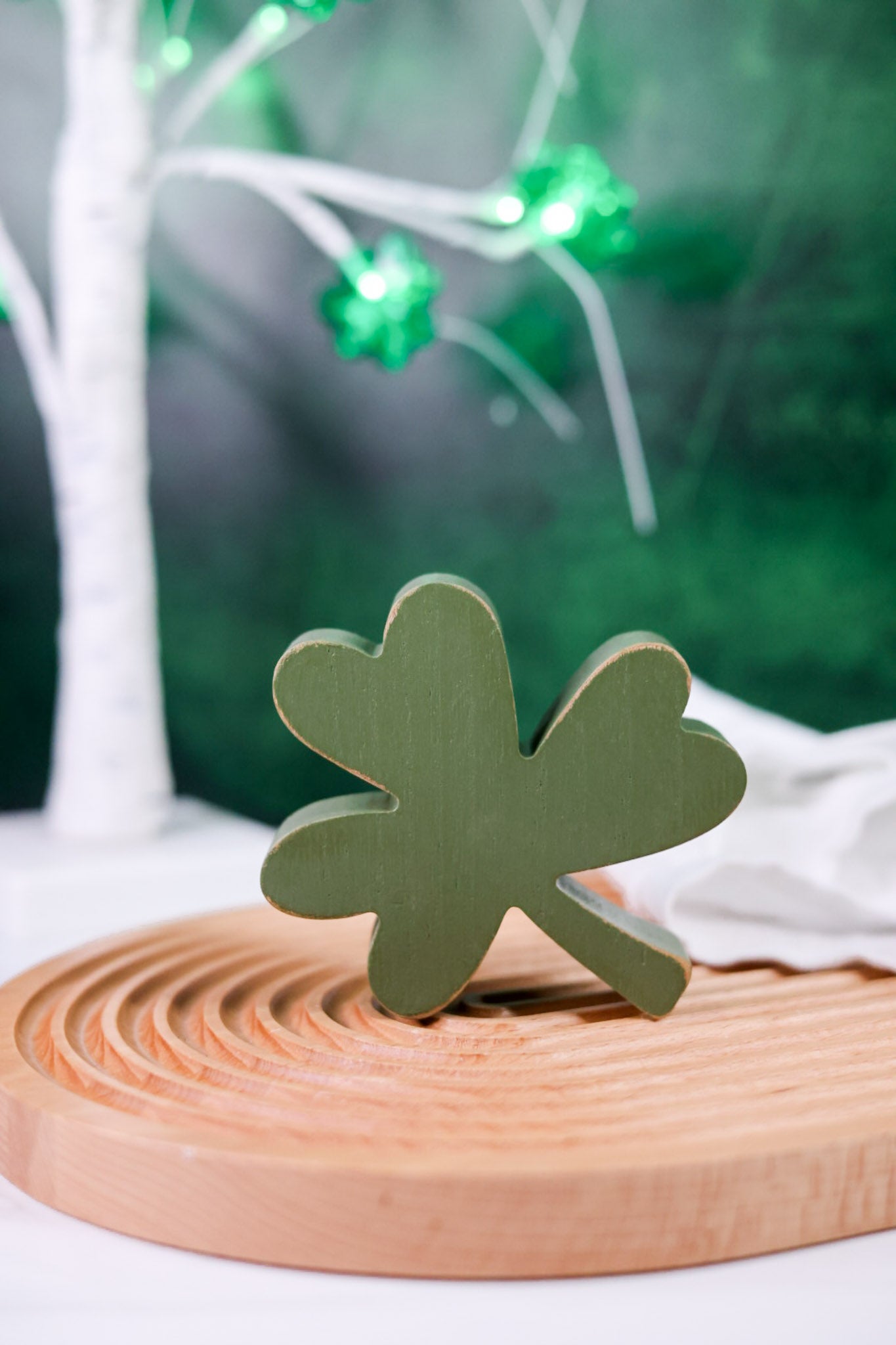 Green wooden clover block from Set of 3 Decorative Wooden Clover Blocks on carved wooden tray with blurred background
