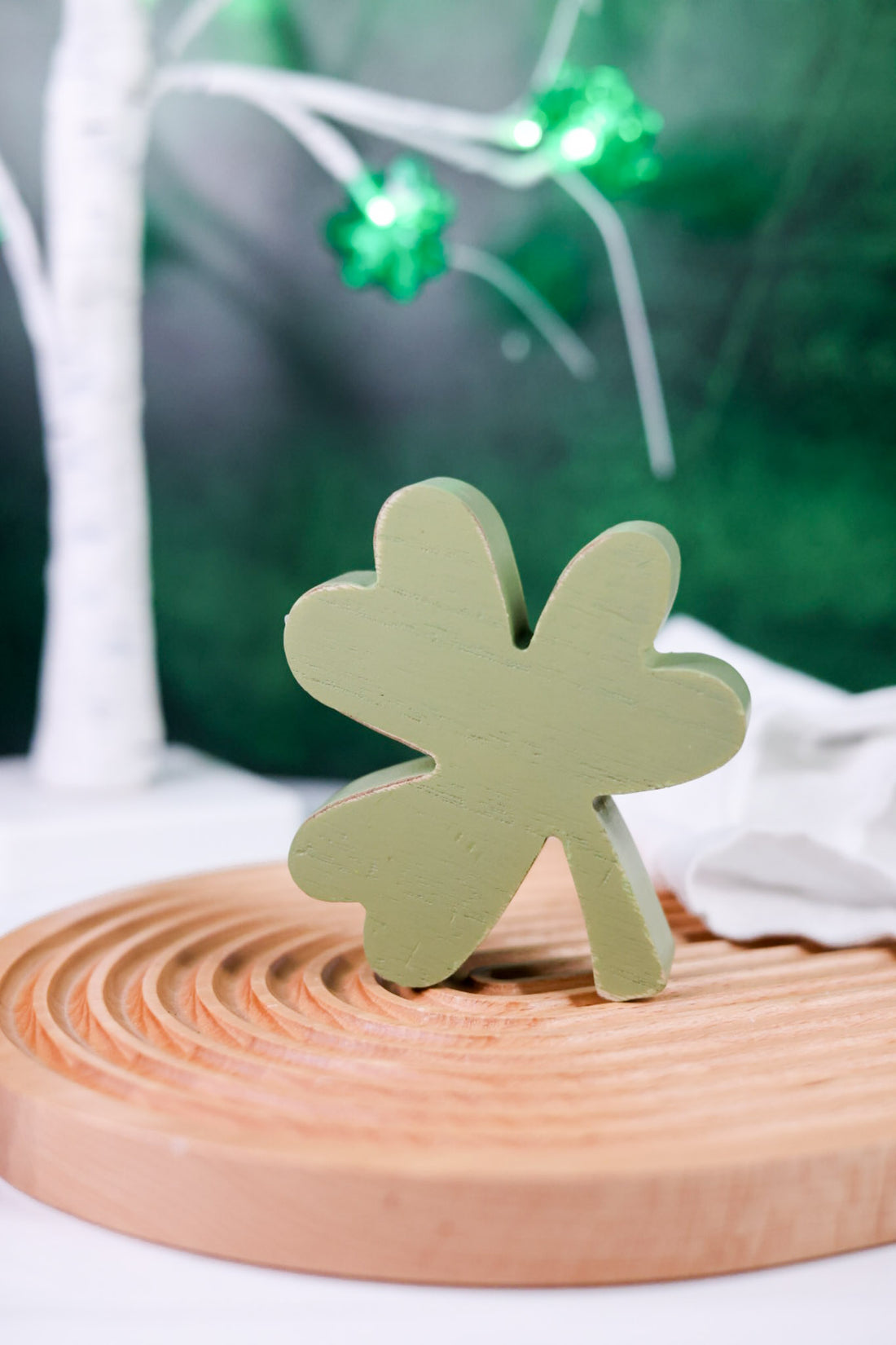 Set of 3 Decorative Wooden Clover Blocks with light green clover block displayed on round wooden tray with blurred background