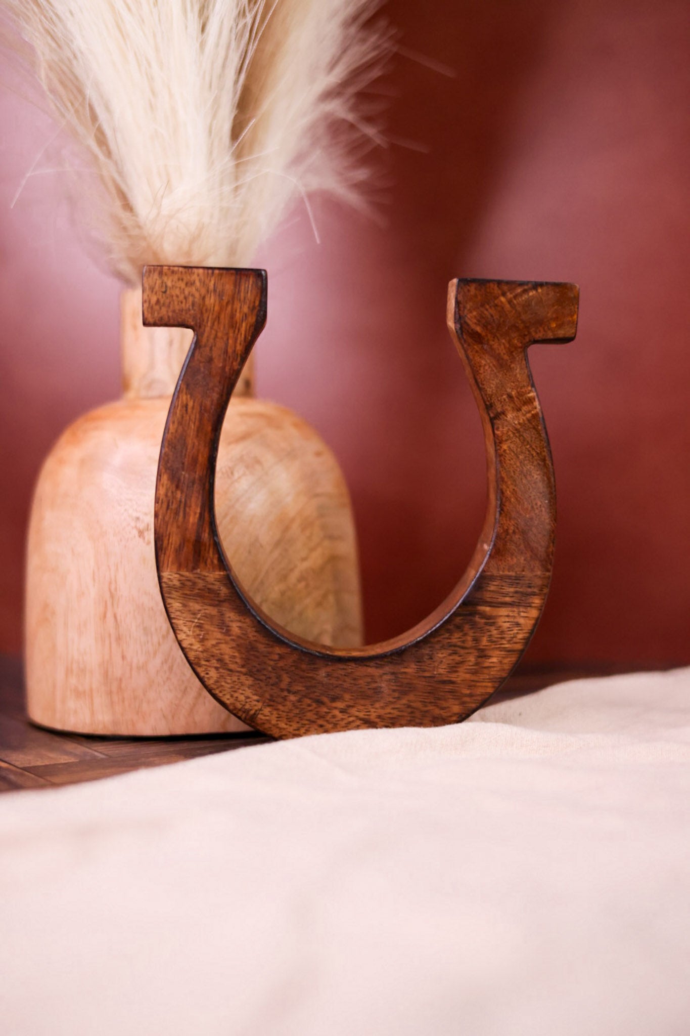Wall Mounted Wooden Horseshoe with smooth finish displayed alongside natural wooden vase and pampas grass decor