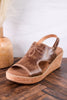 Cognac Faux Leather Wedges With Stitching featuring decorative floral stitch and cork wedge heel on wooden floor background