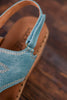 Turquoise Faux Leather Wedges With Stitching showing textured strap and detailed stitching on wooden floor background