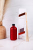 Red Glitter Reed Diffuser With Volcano By Capri Blue with diffuser sticks and sleek white and red packaging on marble surface