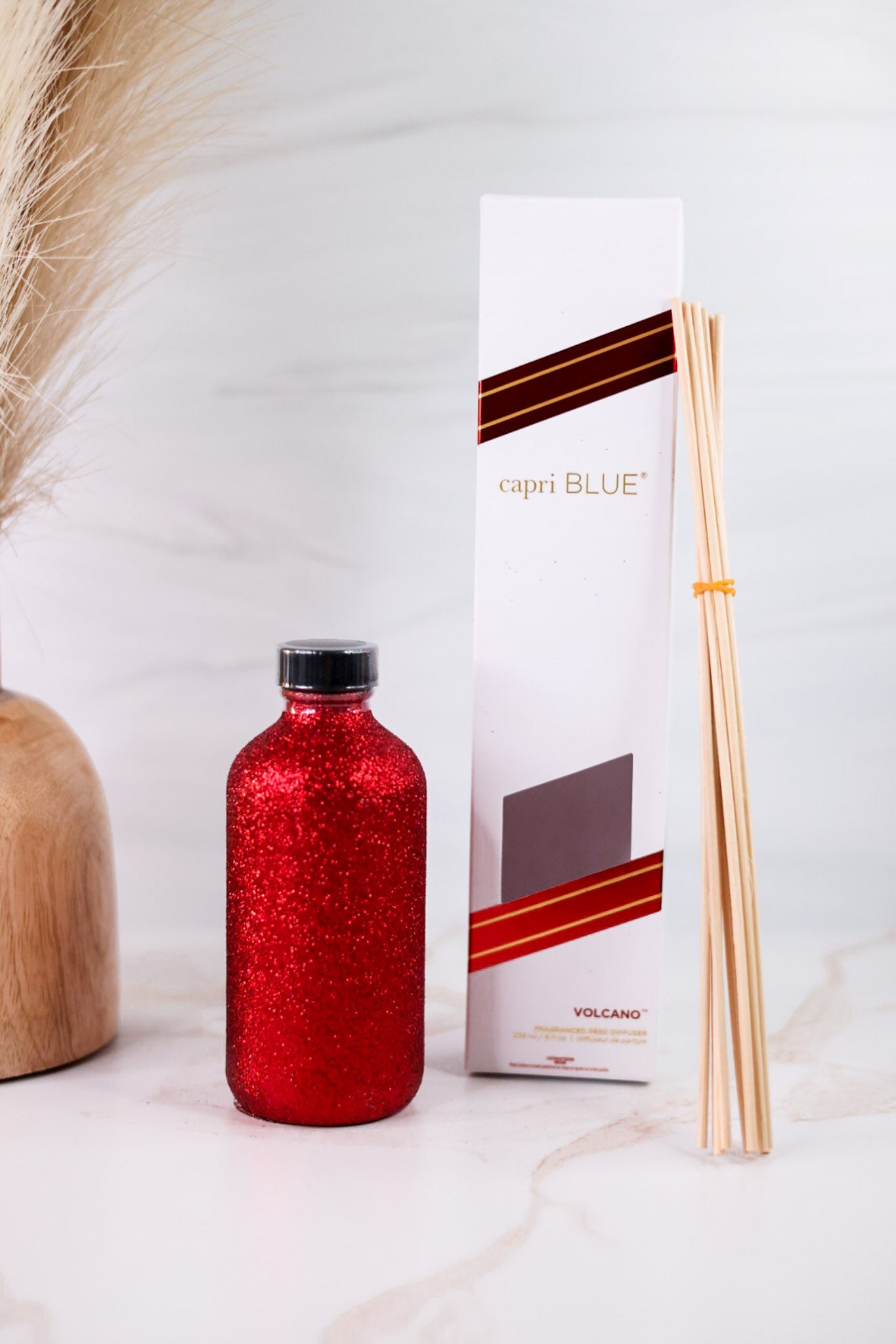 Red Glitter Reed Diffuser With Volcano By Capri Blue displayed with diffuser sticks and sleek packaging on marble surface