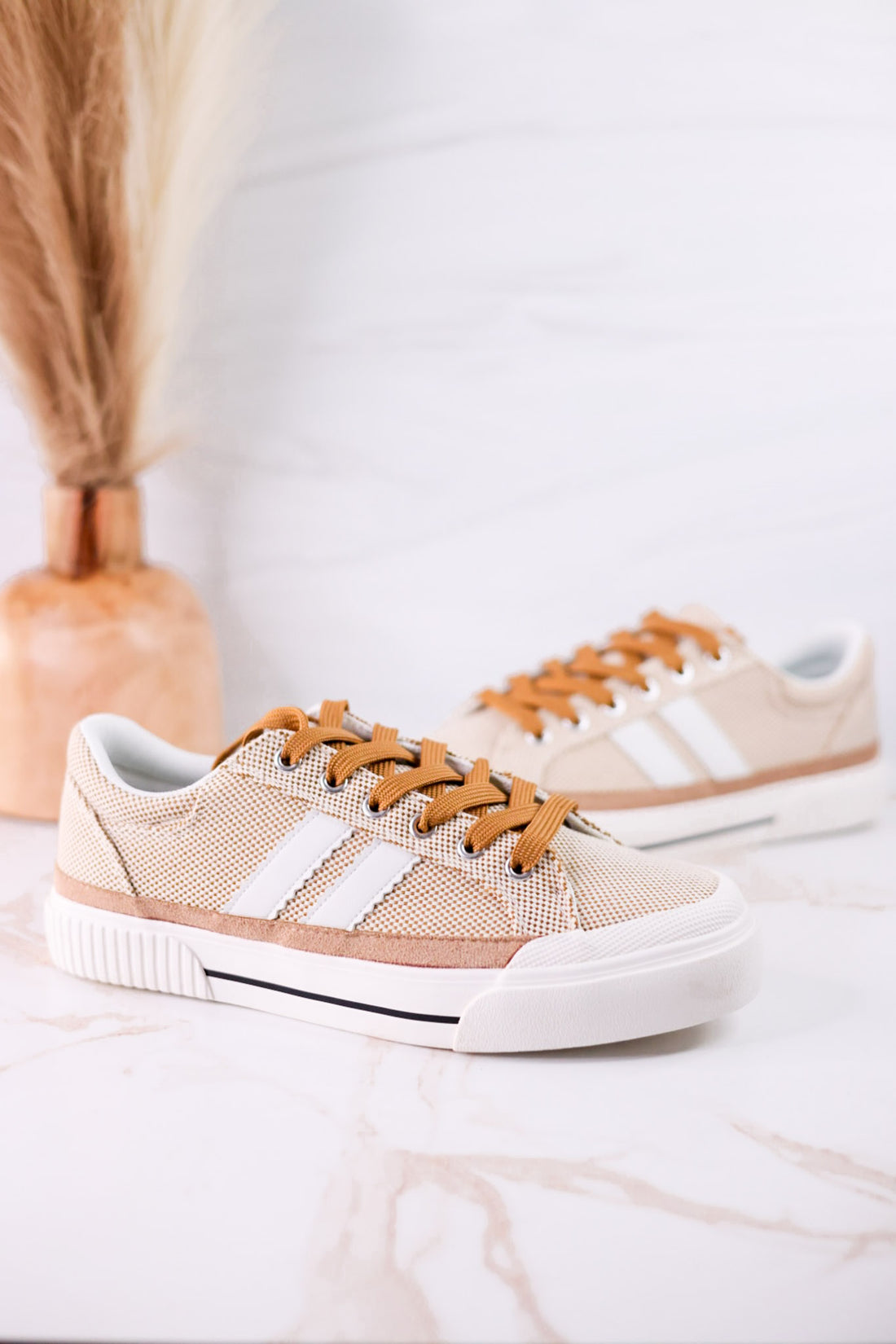That's Her Tan Tweed Sneakers with white stripes and brown laces displayed on marble surface with decorative vase behind