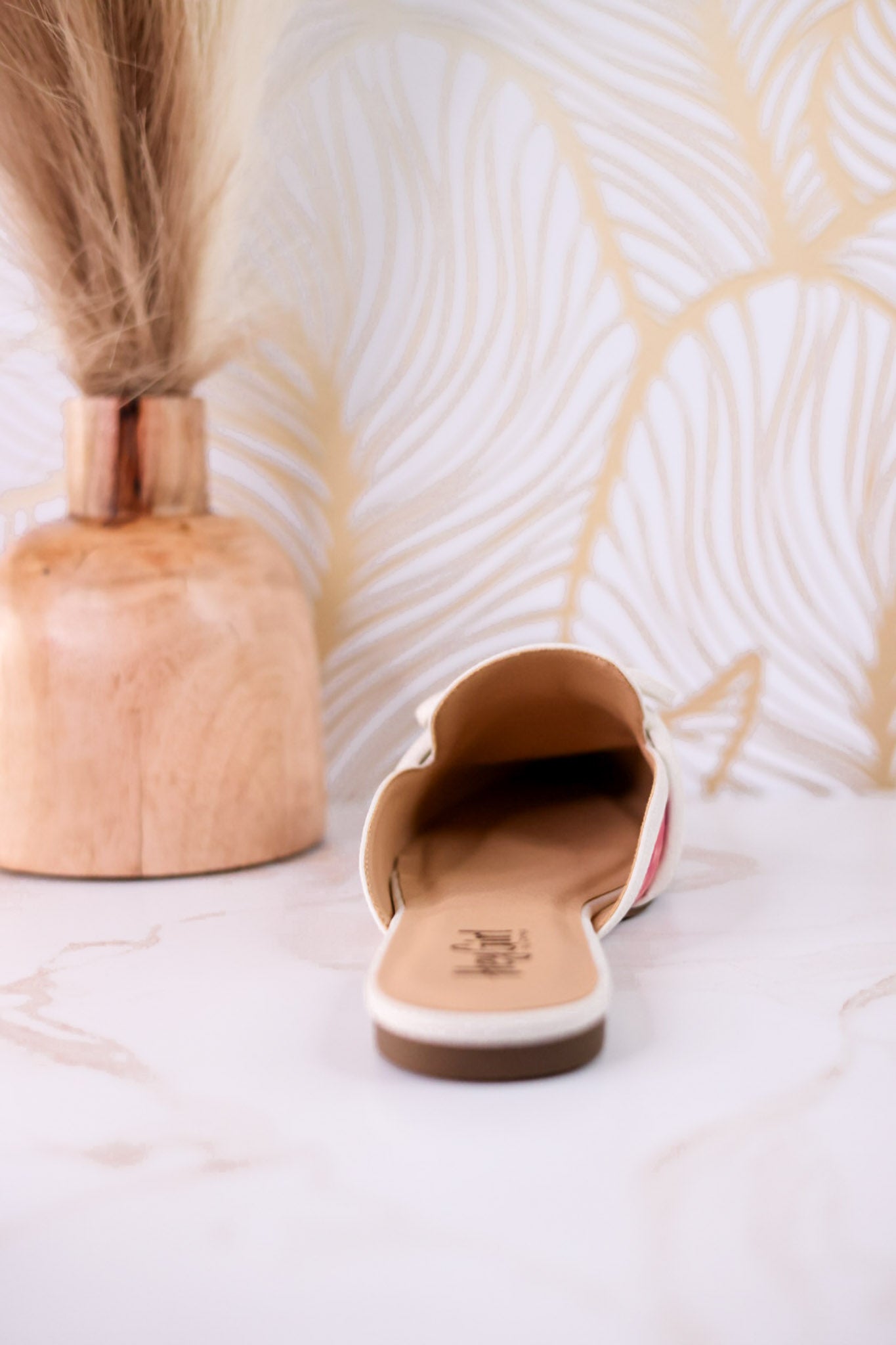 Tip Included Floral Pointed Toe Mules shown from back on marble surface with decorative wooden vase in relaxed setting