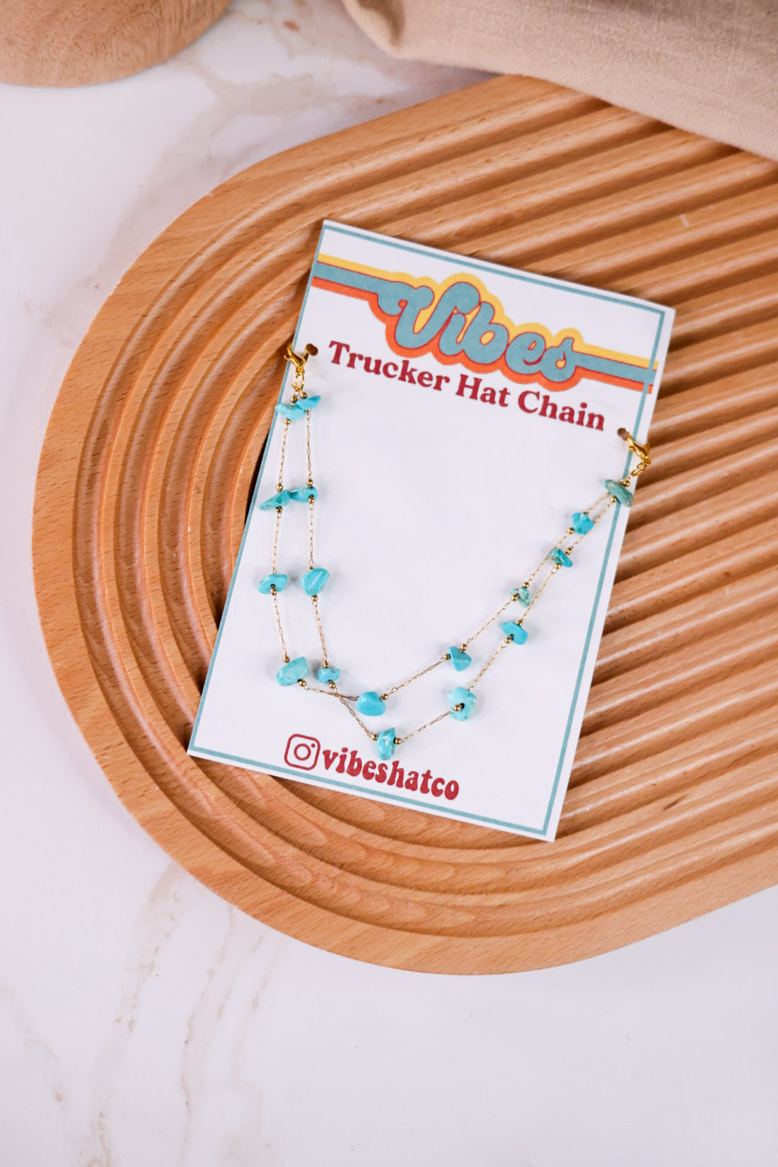 Turquoise Trucker Hat Chain with irregular turquoise stones on delicate gold chain displayed on wooden tray background