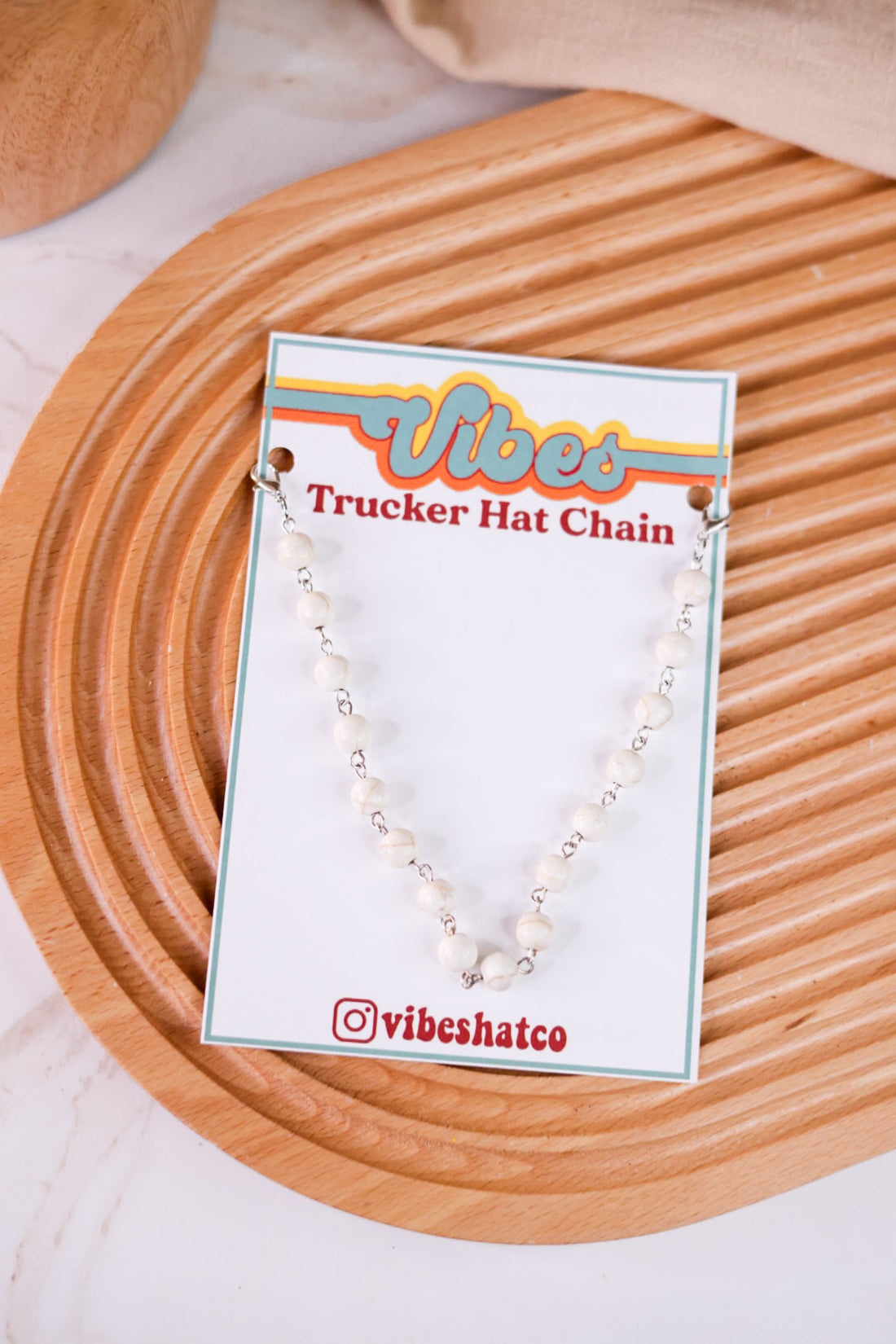 White Turquoise Trucker Hat Chain with white beads and silver links displayed on branded card on wooden textured surface