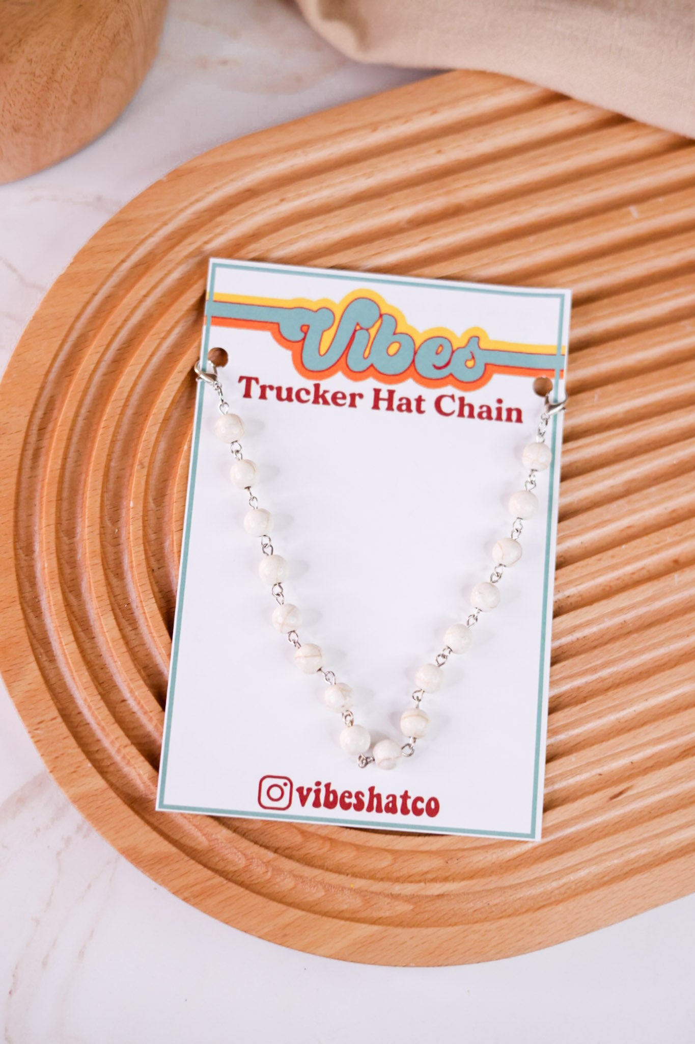 White Turquoise Trucker Hat Chain with white beads and silver links displayed on branded card on wooden textured surface