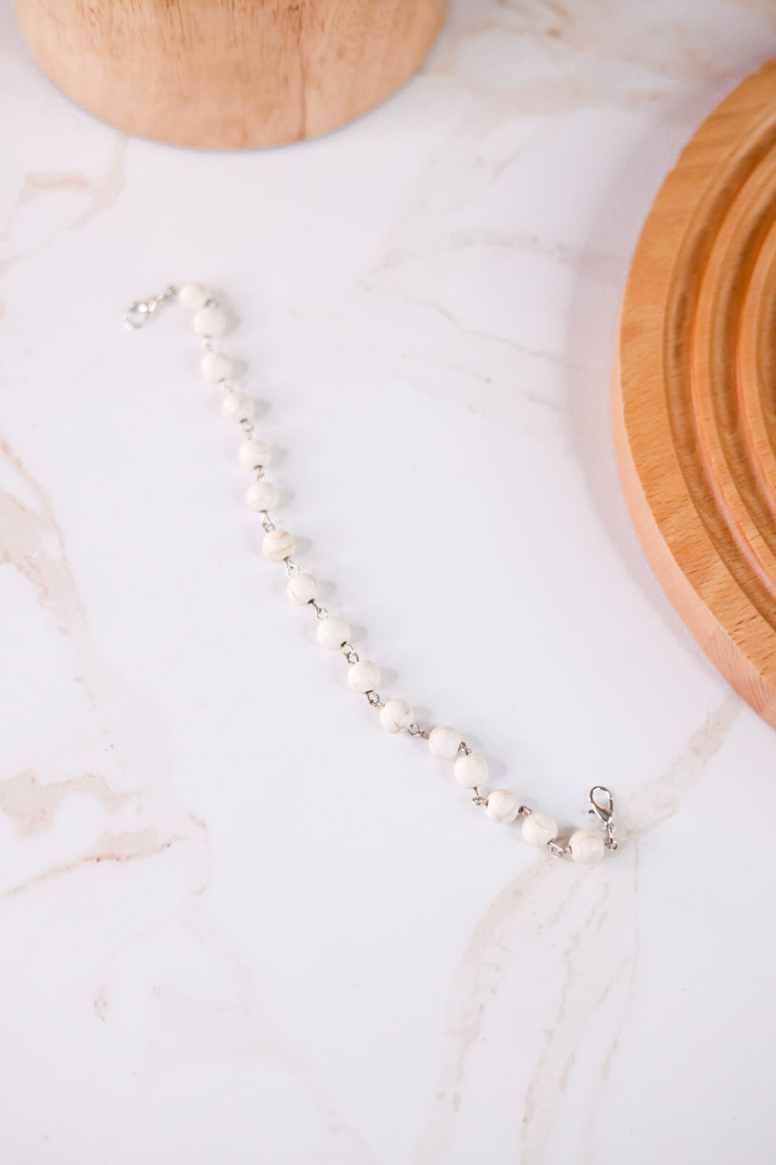 White Turquoise Trucker Hat Chain featuring white beads with silver links displayed on a marble surface with wooden accents