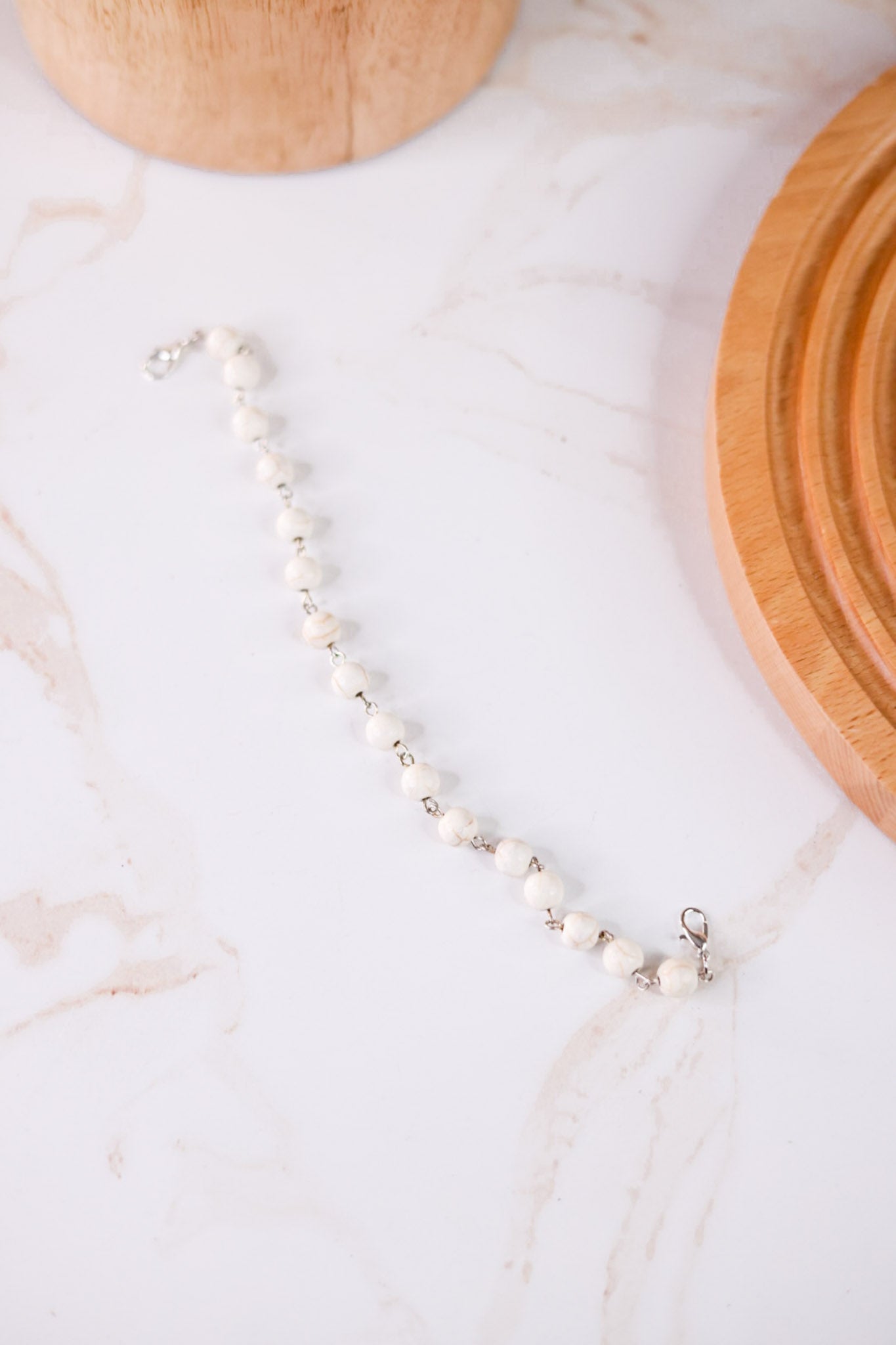 White Turquoise Trucker Hat Chain featuring white beads with silver links displayed on a marble surface with wooden accents