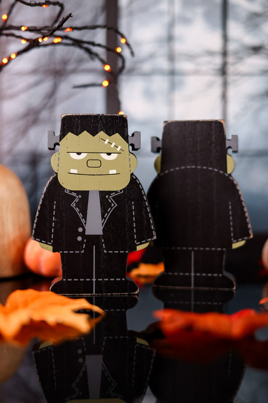 Two paper cutout figures of a monster with a blurred background