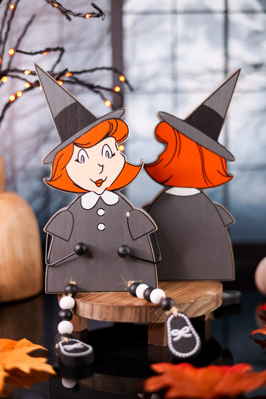 Two paper cutout witches with red hair and black hats on a Halloween-themed background.