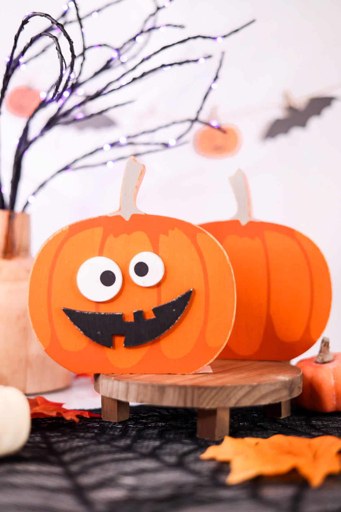 Halloween-themed decorations with pumpkins and decorative branches on a white background.