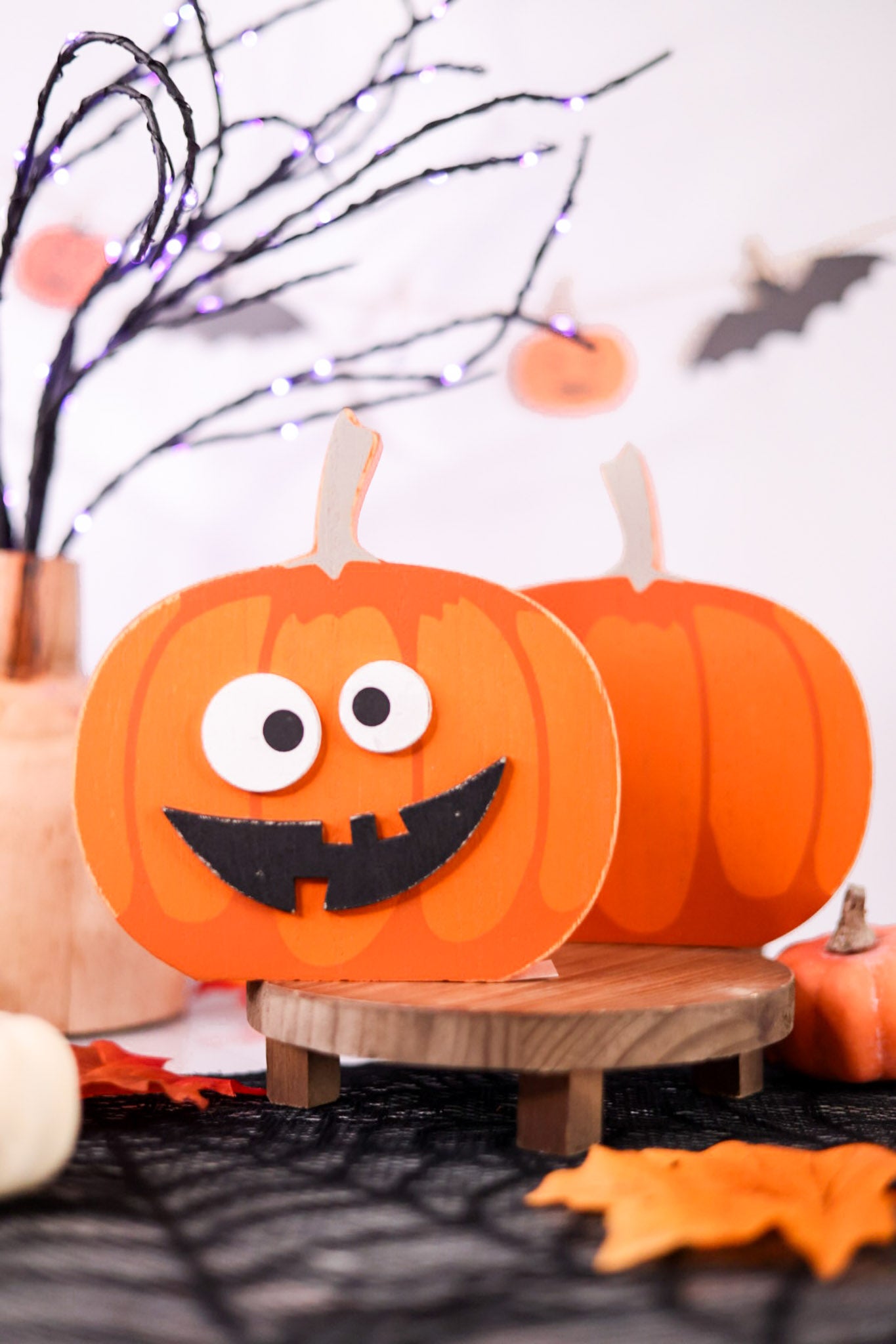 Halloween-themed decorations with pumpkins and decorative branches on a white background.