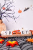 Halloween-themed decor with 'Spooky' sign, pumpkins, and leaves on a spiderweb background.