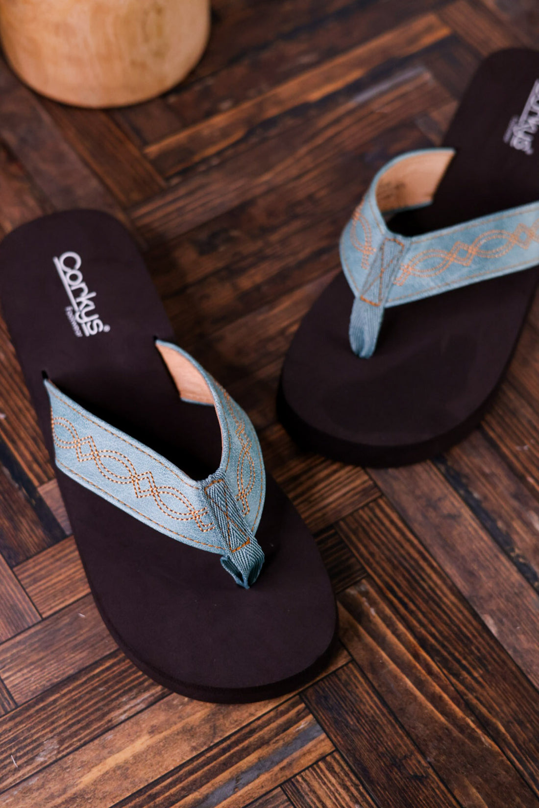 Turquoise Overboard Flip Flops With Embroidered Faux Leather Straps on wooden floor showcasing comfortable durable shoes