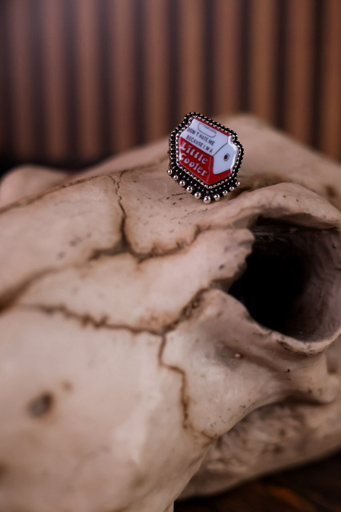 Little Cooler Adjustable Cuff Ring featuring cooler design displayed on rustic animal skull with blurred background