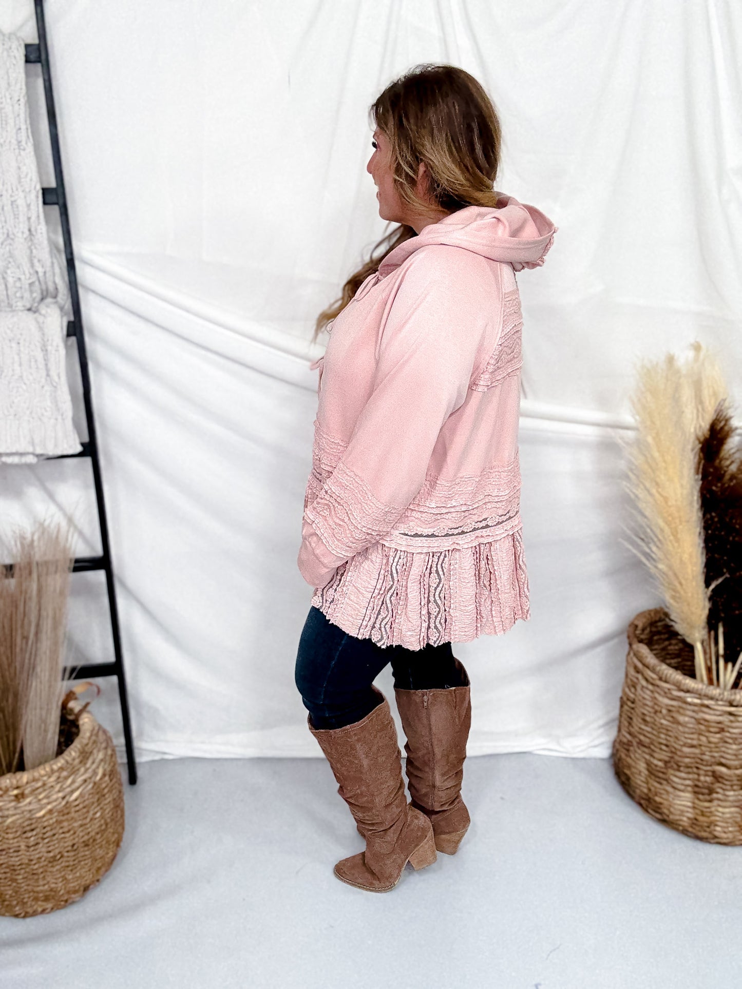 Profile view of woman wearing Dusty Pink Laced Front Tie Hooded Jacket Cardigan with dark jeans and brown boots indoors