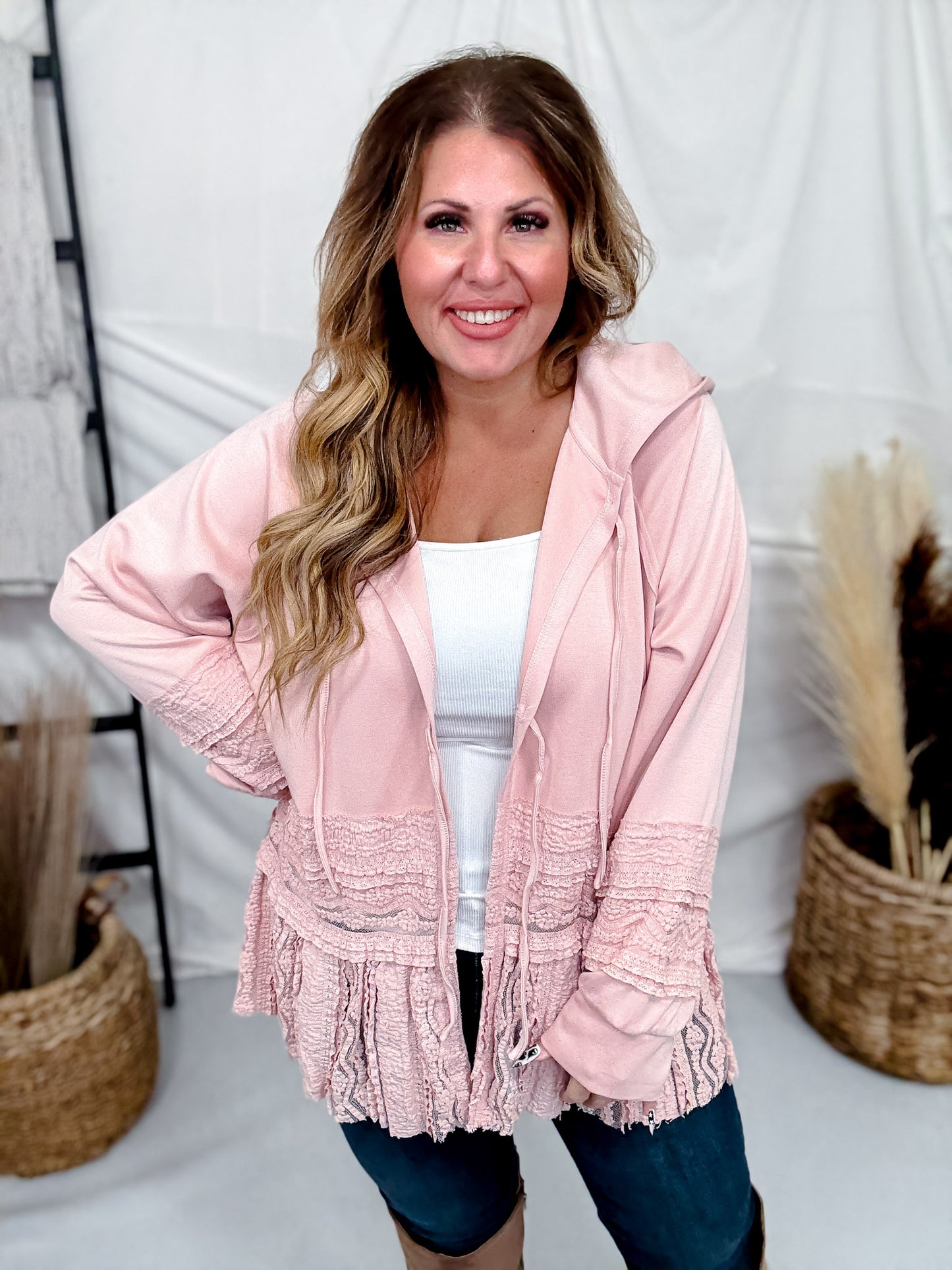 Woman wearing Dusty Pink Laced Front Tie Hooded Jacket Cardigan styled with white top and dark jeans indoors