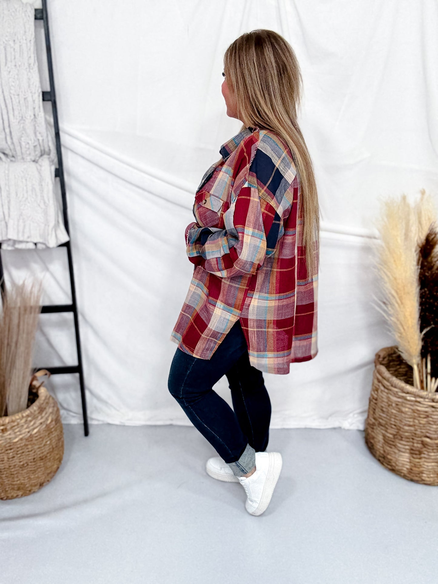 Woman wearing Wine & Navy Plaid Button Down Flannel With Shirred Sleeves styled with dark jeans and white sneakers in cozy setting