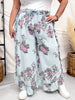 Front view of woman wearing Light Blue Floral Chambray Pants With Ruffled Hem featuring a floral print and relaxed fit indoors