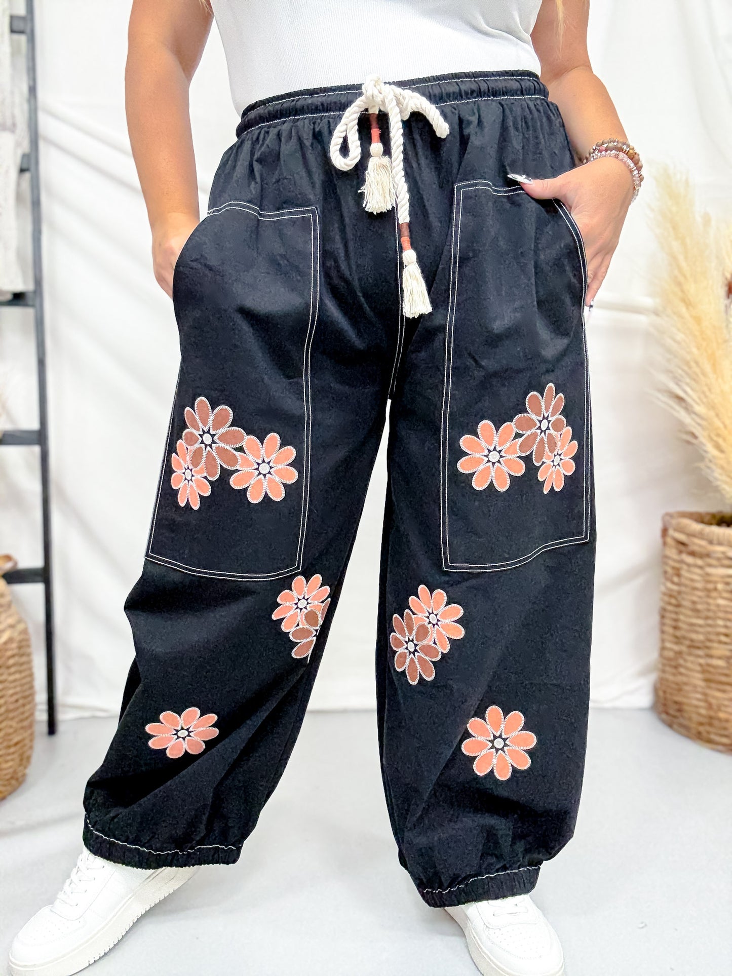 Model wearing Black Drawstring Waist Cropped Pants With Floral Appliques featuring large front pockets and comfortable fit indoors