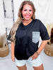 Smiling woman wearing Crewneck Denim Pocket Black Tunic Top with light denim shorts in bright indoor setting
