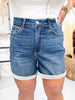Judy Blue High Waist Tummy Control Cool Denim Shorts shown on model with rolled cuffs and casual white top indoors