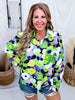 Smiling woman wearing Green & Purple Floral Print Button Down Top styled with distressed denim shorts indoors