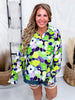Woman modeling Green & Purple Floral Print Button Down Top with long sleeves and relaxed fit paired with denim shorts indoors