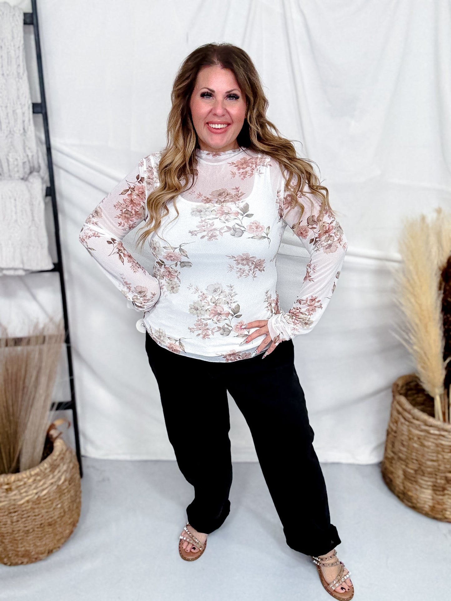 Smiling woman modeling Ivory & Taupe Floral Print Long Sleeve Mesh Top paired with black pants in bright indoor setting